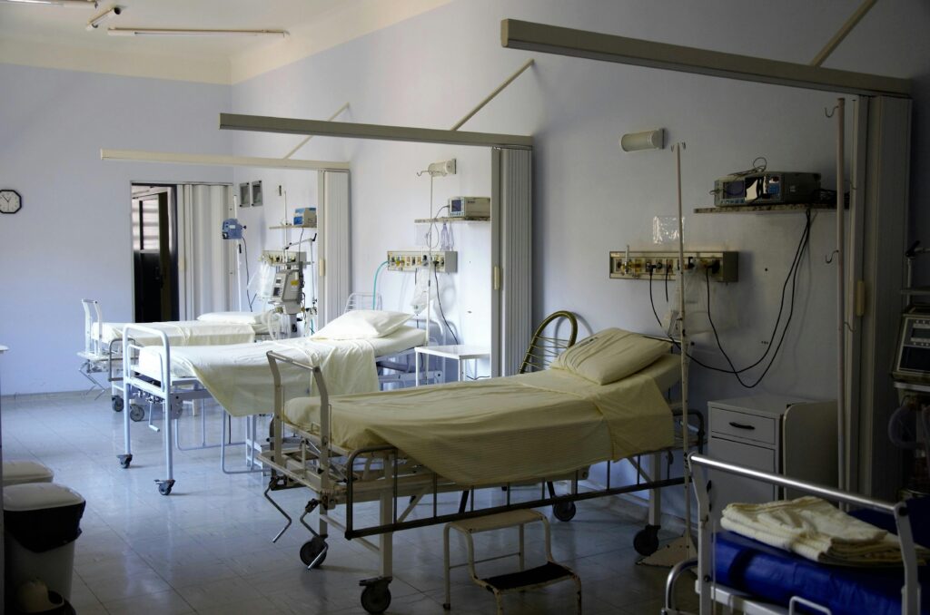 Spacious hospital room with several empty beds and medical equipment, emphasizing healthcare and hygiene.